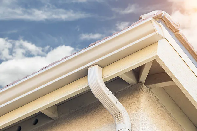 Closeup image of a white gutter and downspout