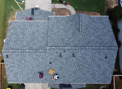 Image of roofer on a roof repairing damaged shingles