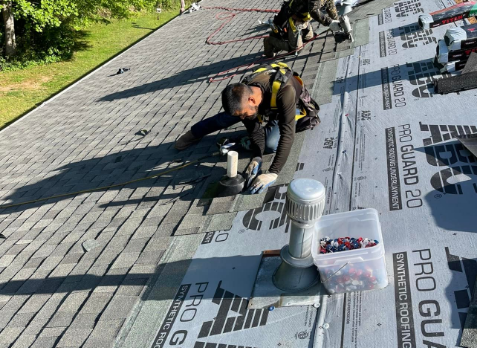 Image of roofer on a roof repairing damaged shingles