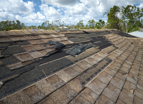 Image of a brown roof with damaged and missing shingles