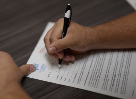 Photo of a hand filling out an insurance claim form on a desk