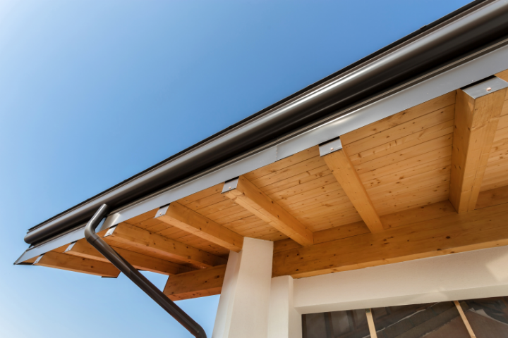 Photo looking up at a corner of a roof with a new black gutter installed