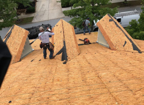 Photo of roofers on a on a roof without shingles