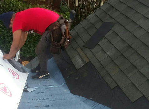 Roofer on roof repairing damaged shingles