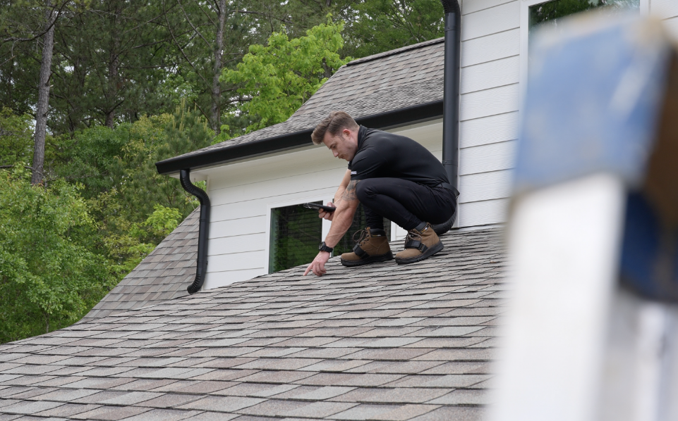 Photo of a roofer on top of a roof performing a roof inspection