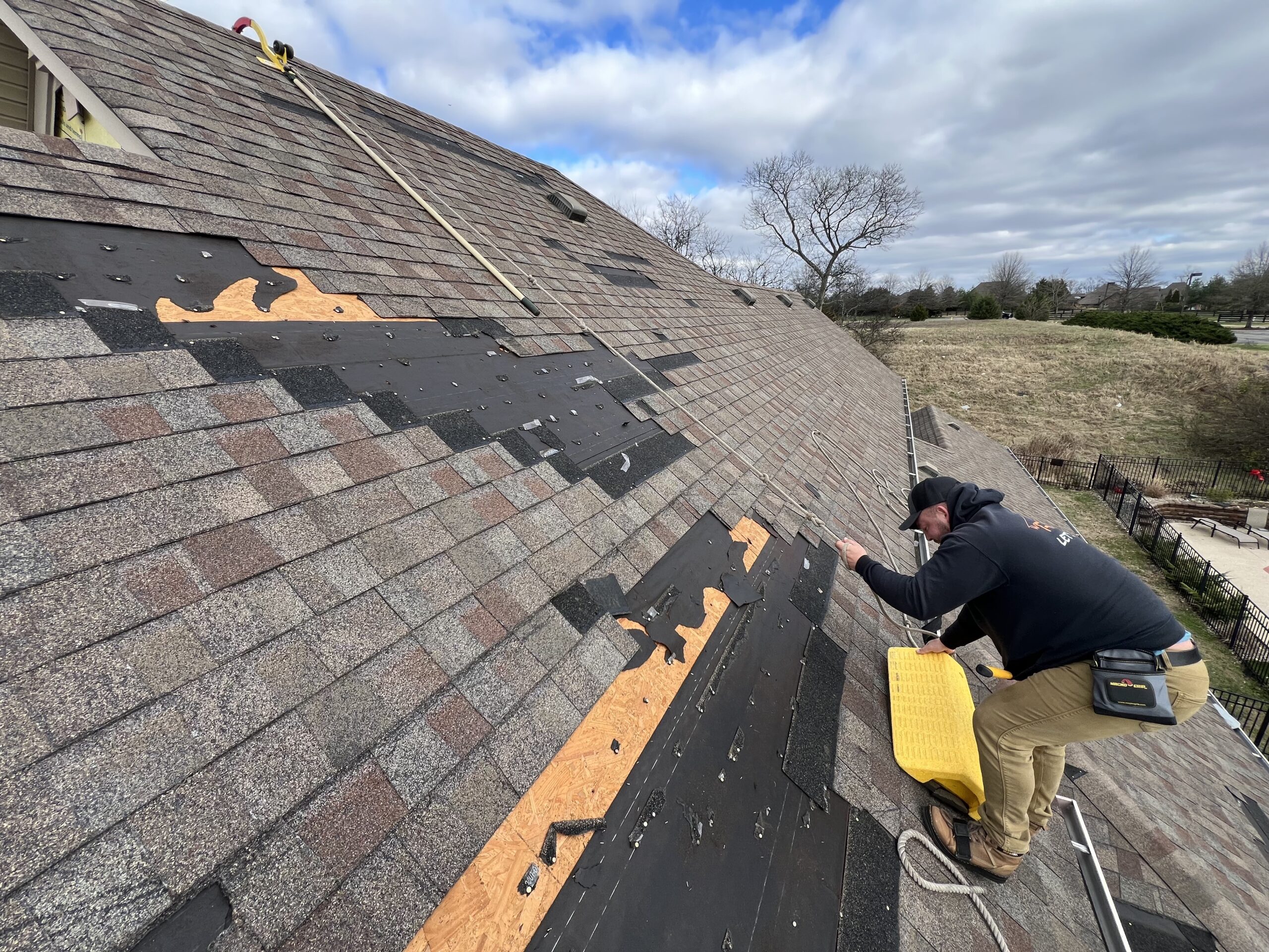 Photo of roof contractors replacing shingles on a roof with roof storm damage