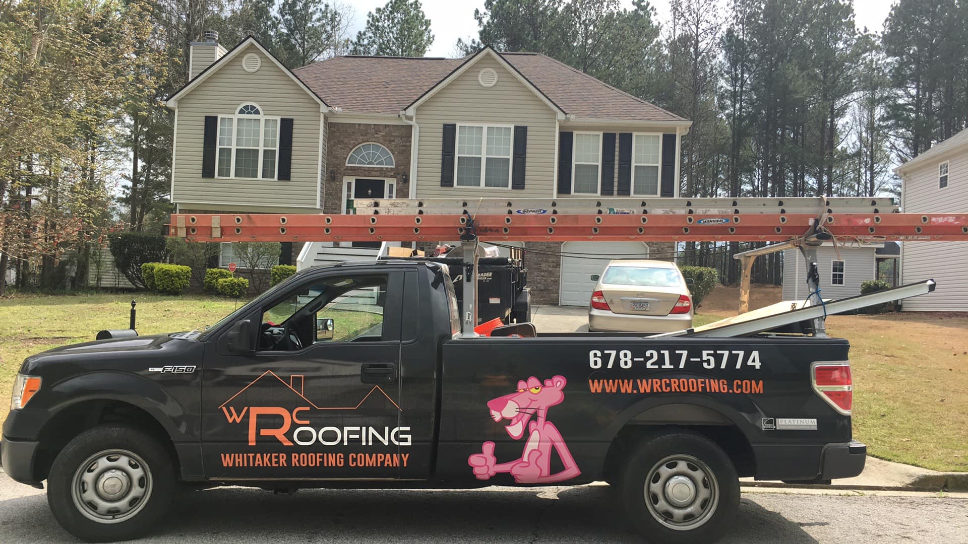 Photo of a Whitaker Roofing Company truck parked in front of a residential home