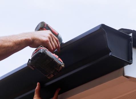 Up close image of a hand installing a new gutter on a house