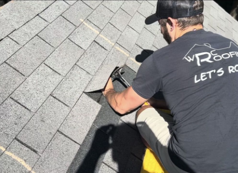 Roofer on a home with gray shingles during a roof repair