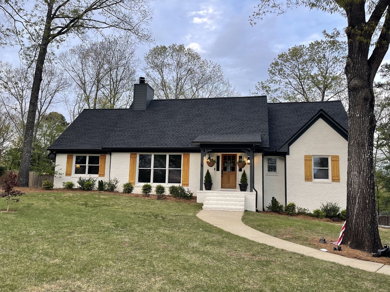 Quality roofing installed on house. Black asphalt shingles on an off white house.