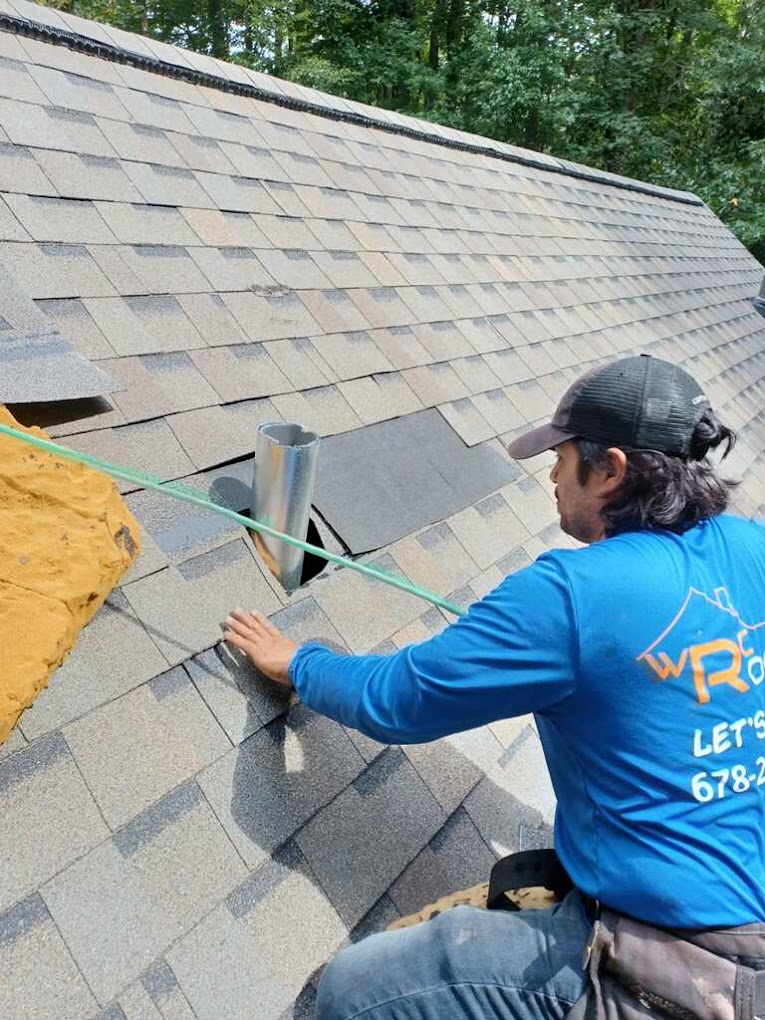 Roofer on a home with gray shingles during rooftop repairs