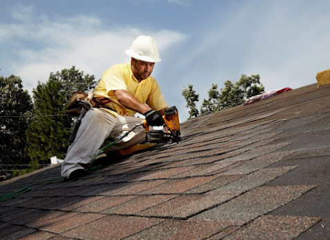 Roofer on a home with brown shingles during a roof repair