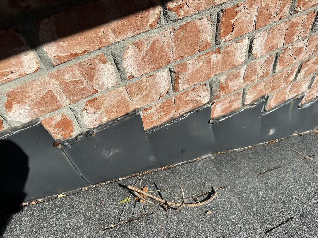 Closeup image pointing out potential shingle issues during commercial roof maintenance of a brick building