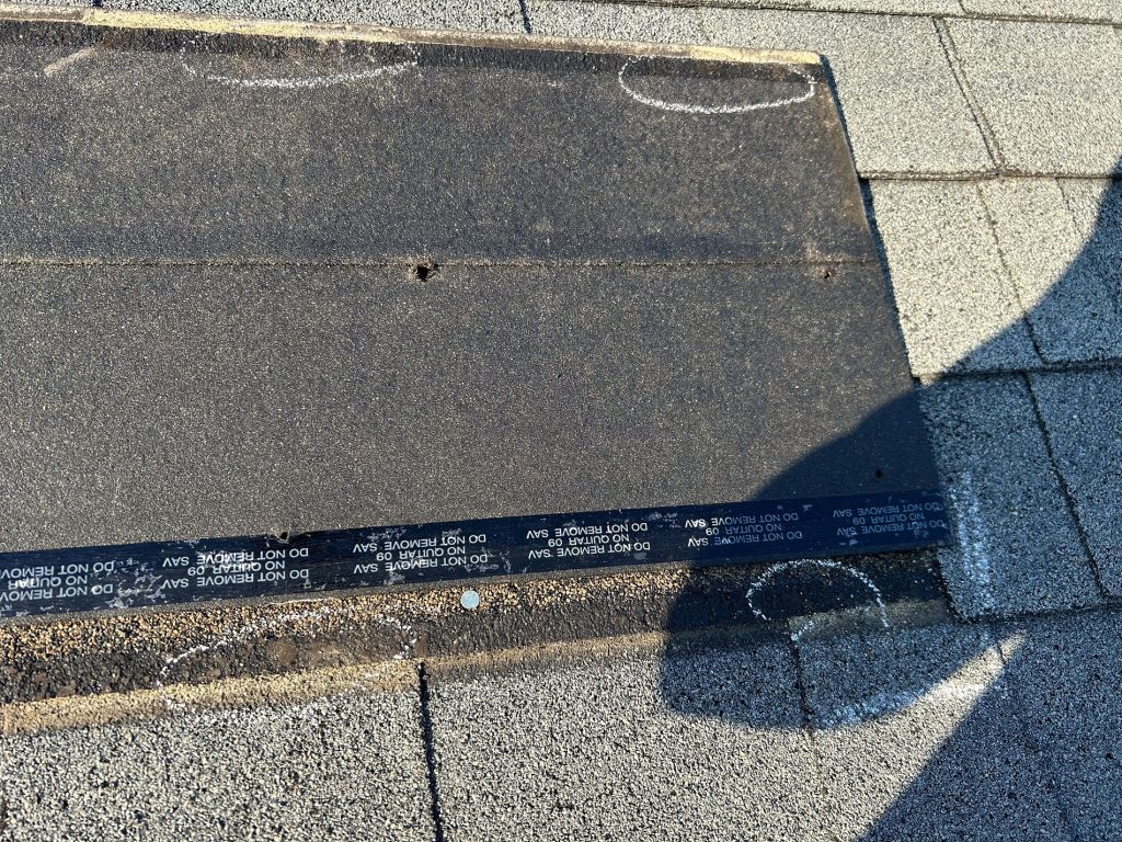 Closeup image pointing out potential shingle issues during commercial roof maintenance