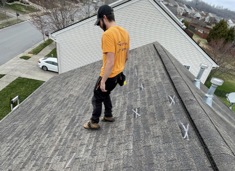 Image of a roofer on a residential shingle roof during roof inspection