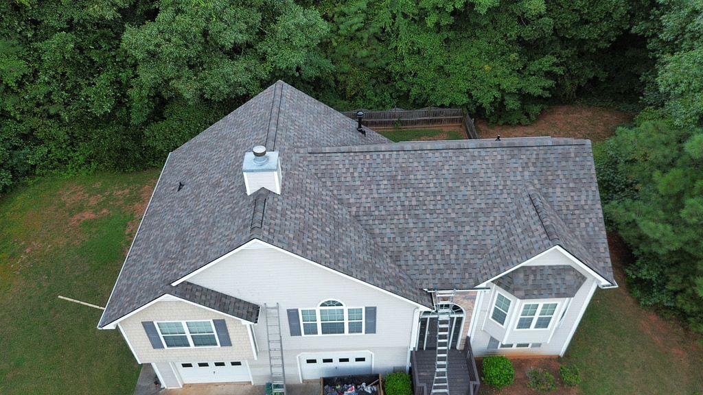 aerial image of a new gray roof on a white house from a local roofing company