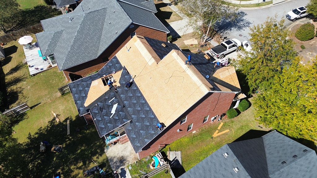 aerial image of roofers from local roofing company replacing a residential roof on a brick house