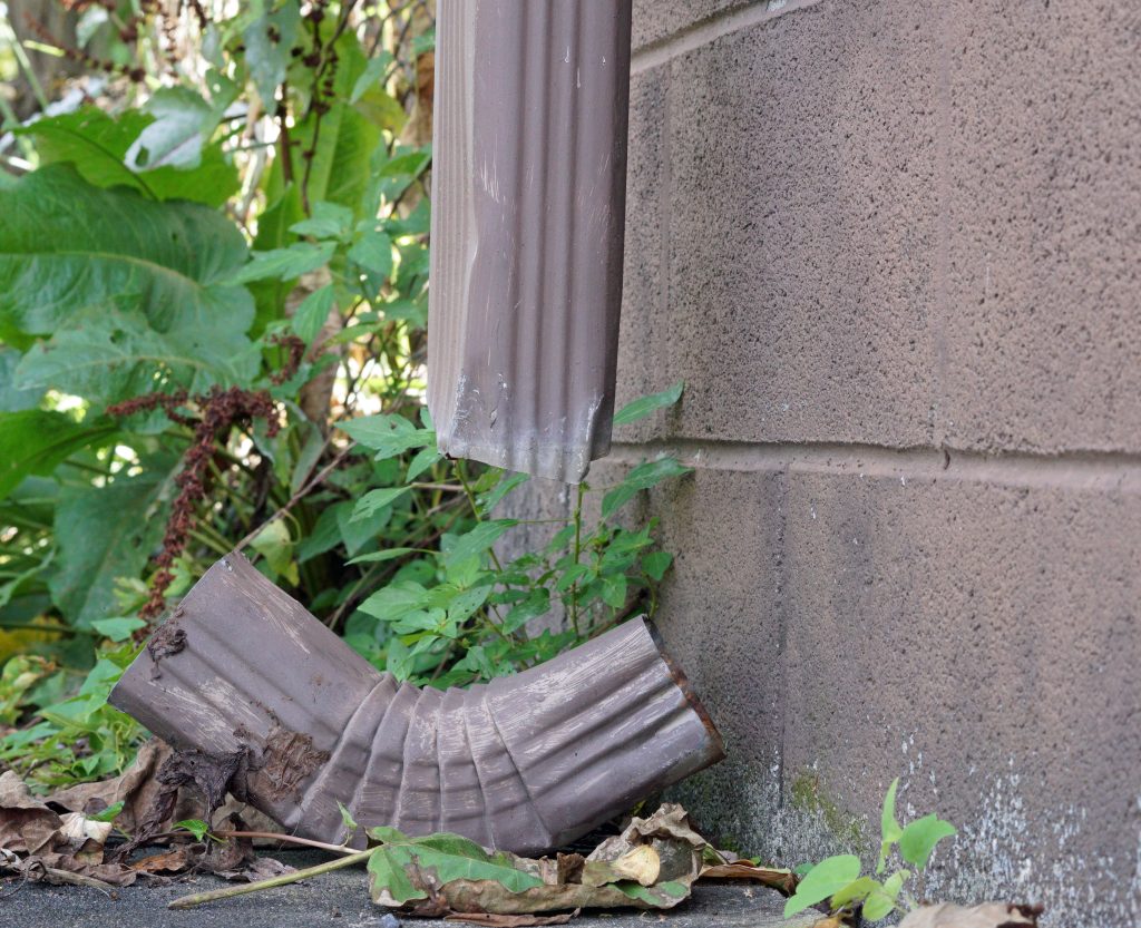 Upclose photo of a damaged downspout on a home