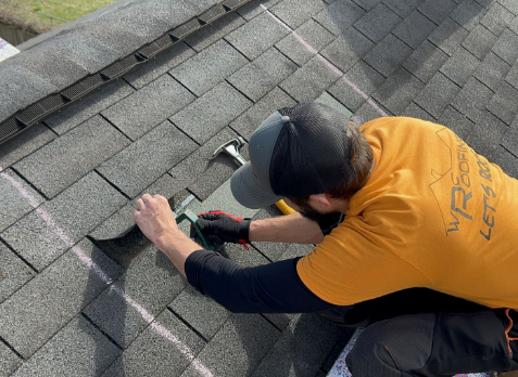 Roofer on roof repairing damaged shingle