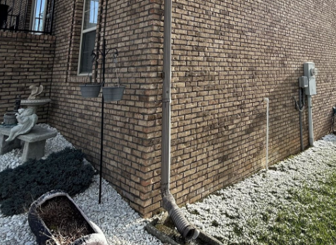 Up close image of a new gutter downspout installed on a brick house