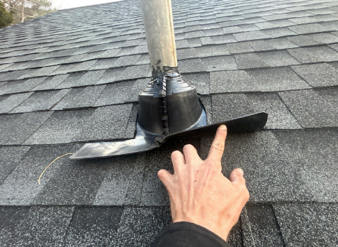 Image of a roofers hand inspecting a residential shingle roof during a roof inspection