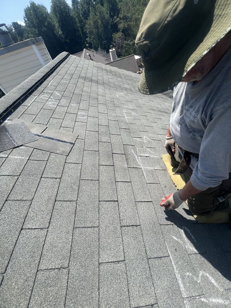 Image of a roofer on a residential shingle roof during roof inspections