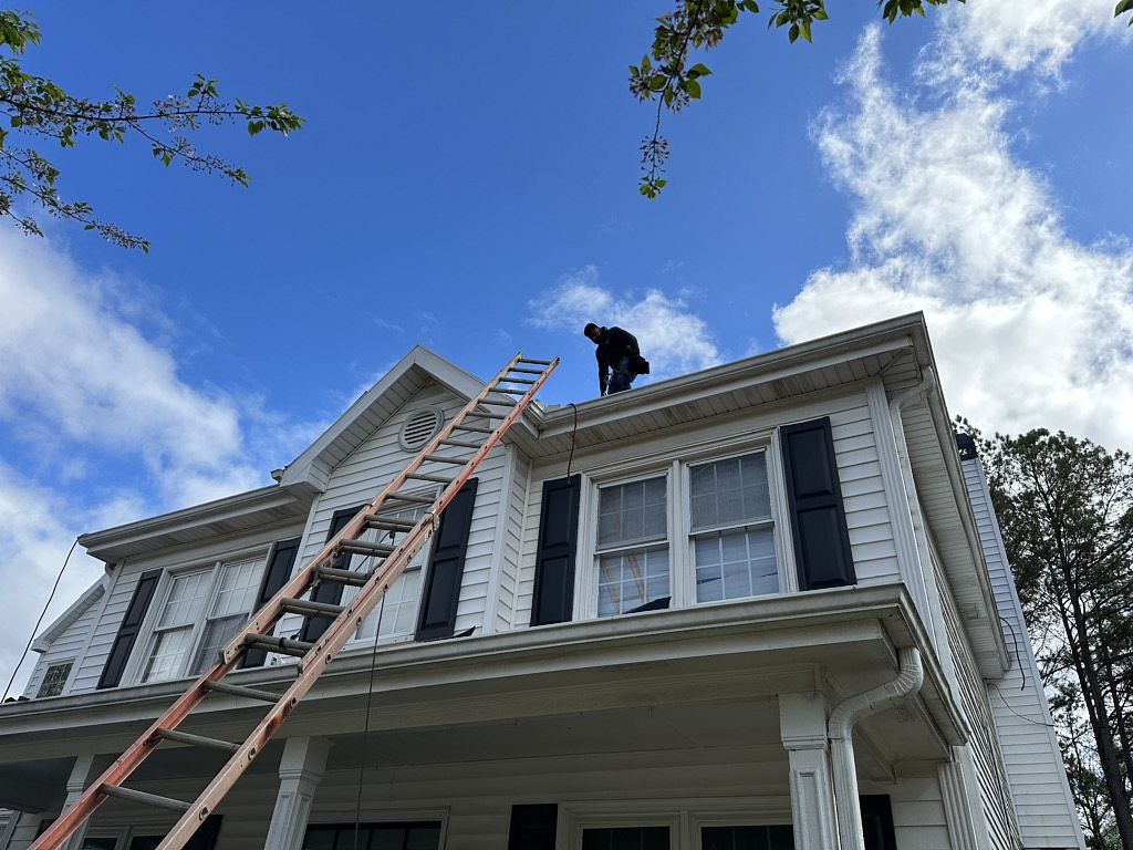 Photo looking up at a roofer on the roof during roof inspections service.