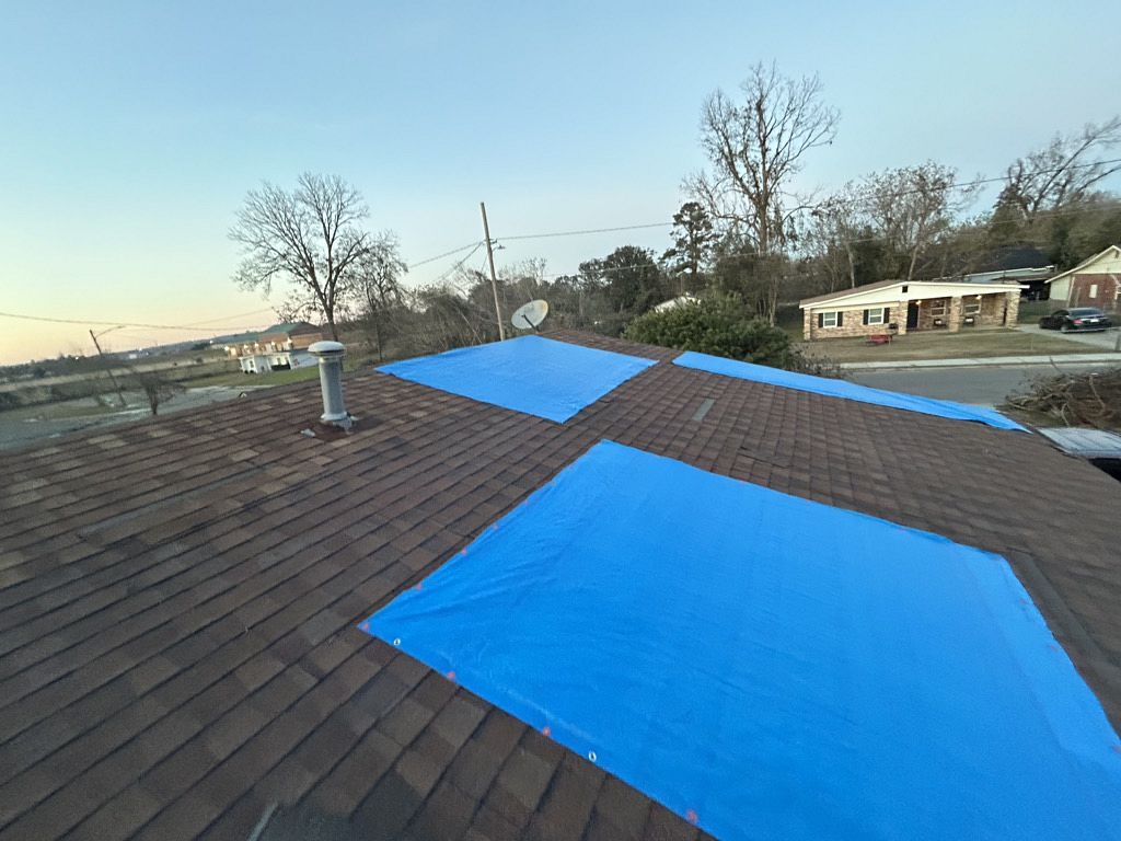 Image of a roof with multiple blue tarps needing roof repairs