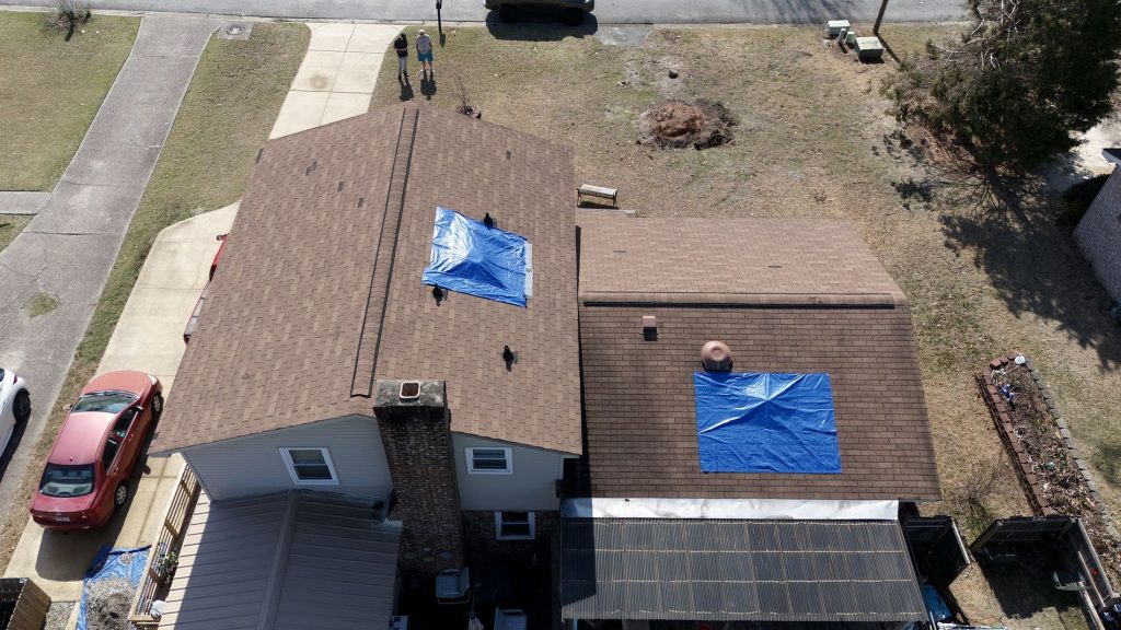 Drone Image of a residential roof with two blue tarps in need of rooftop repairs