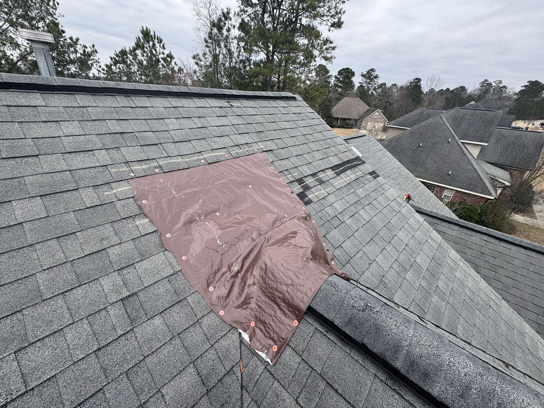 Image of a residential roof with a brown tarp in need of rooftop repairs