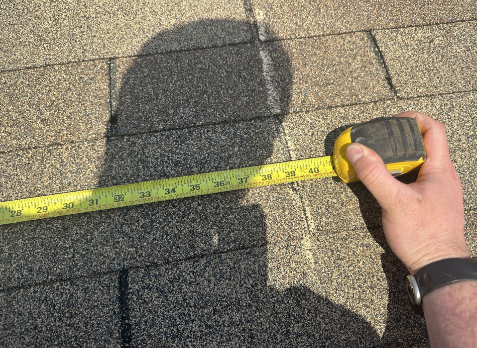 Image of a roofers hand inspecting a residential shingle roof during a roof inspection
