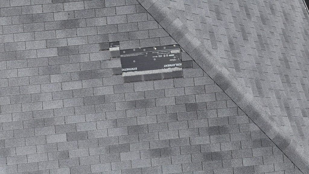 Aerial photo of roof inspection on a roof missing shingles after hail storm with drone