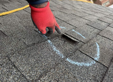 Image of a roofers hand inspecting a residential shingle roof during a roof inspection