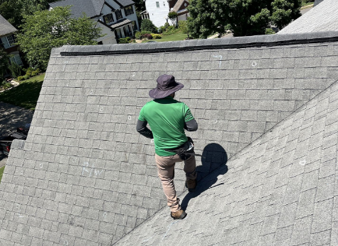 Image of a roofer inspecting a residential shingle roof during a roof inspection