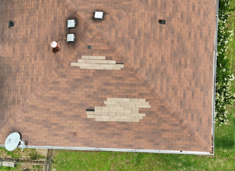 Close up image of brown roof with missing asphalt shingles after storm damage
