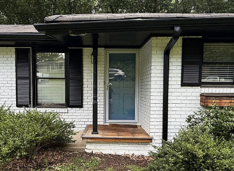 Image of a white house with newly installed Black Gutters and downspouts