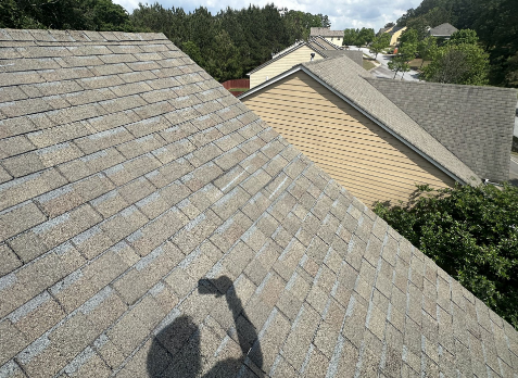 Image of a roofer taking a photos of residential shingle roof during roof inspections