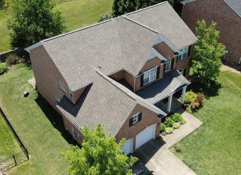 Image of a new brown asphalt shingled roof replacement on a red brick house.