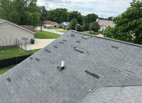 Image of gray roof with missing asphalt shingles after storm damage in Belle Meade.