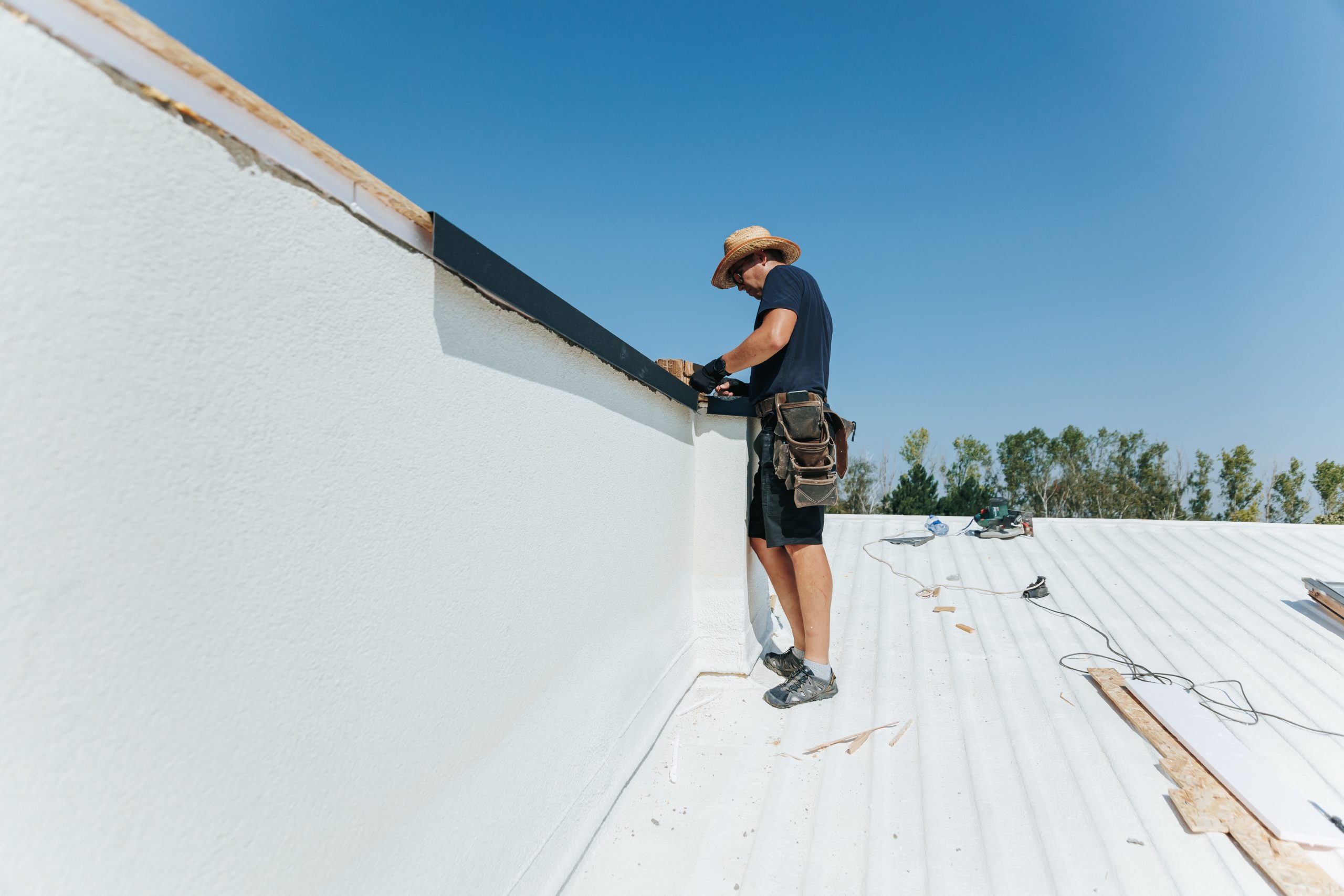 An industrial worker carries out repairs on the construction site installing roofing drip edge.
