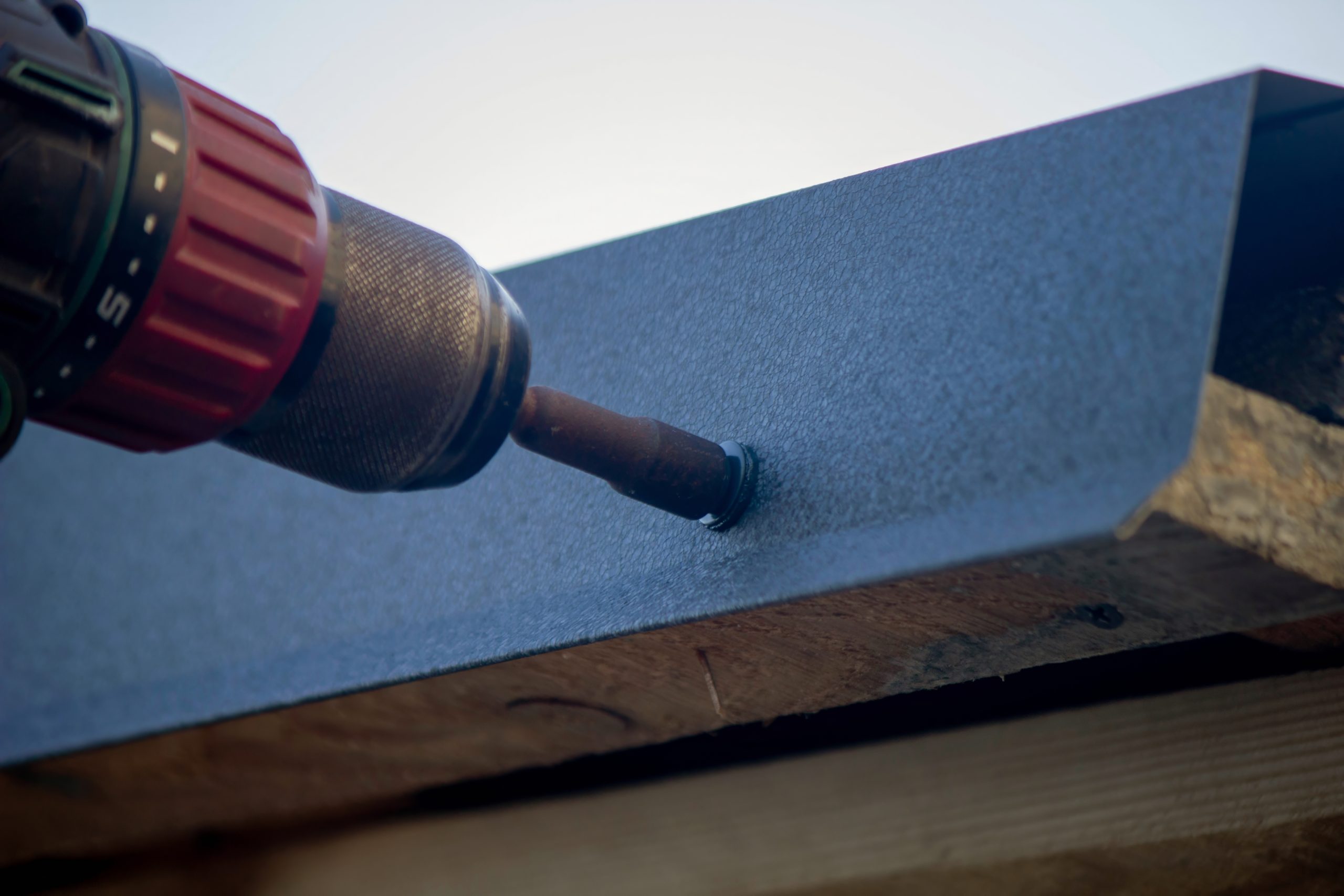 Closeup of drill while repairing roof putting new roofing drip edge.
