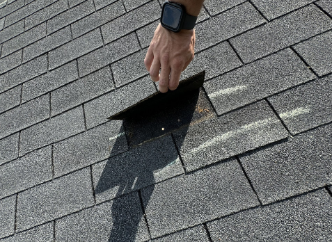 Image of a roofers hand inspecting a residential shingle roof during a roof inspection in Wedowee.