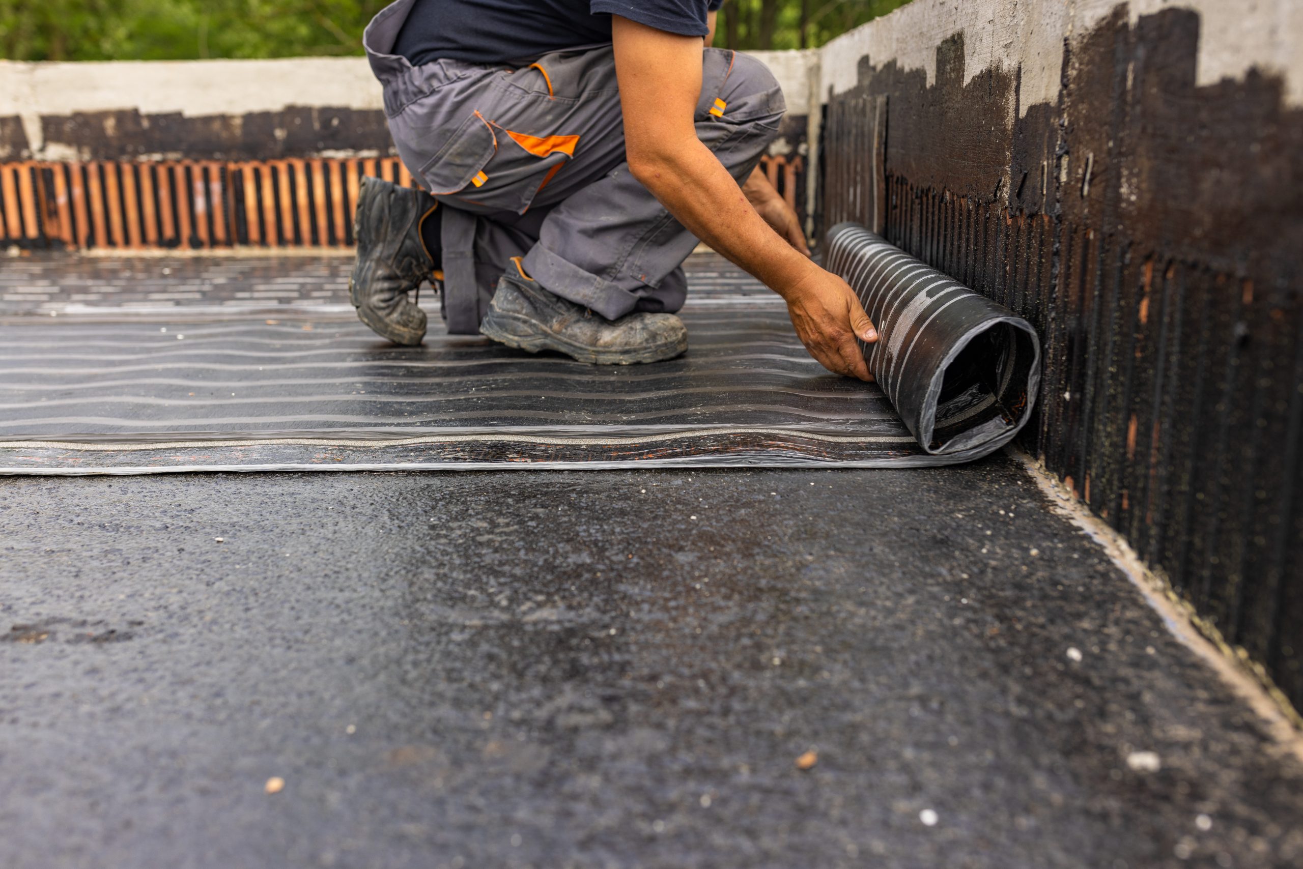 Worker laying a vapor barrier during a flat roof repair.