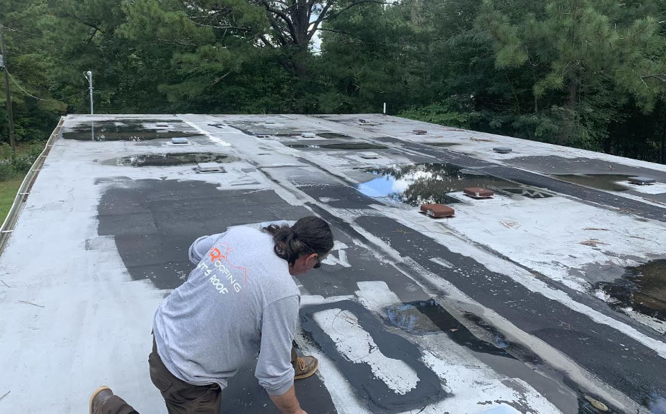 Roofer on flat roof repairing roof with pooling issues