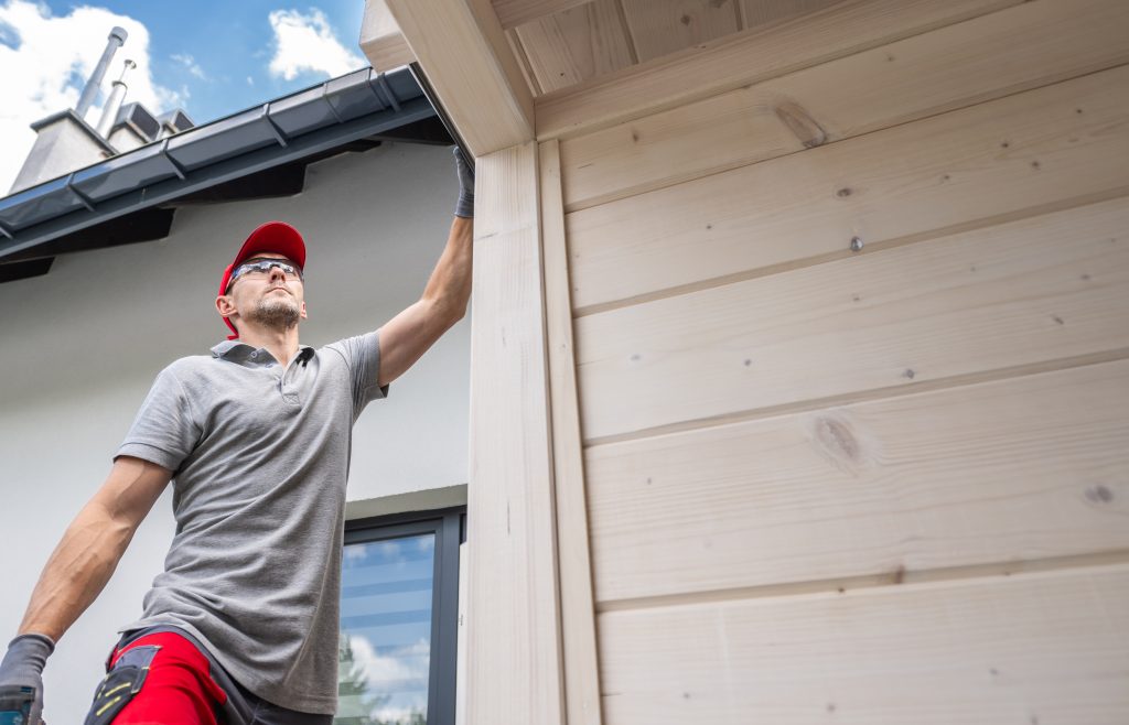 A person is inspecting a roof from a ladder