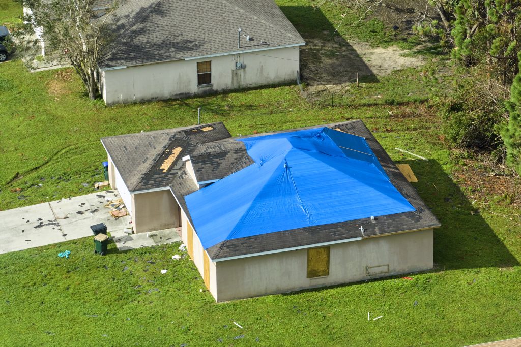 Top view of house needing leaking roof repair covered with protective tarp sheets.