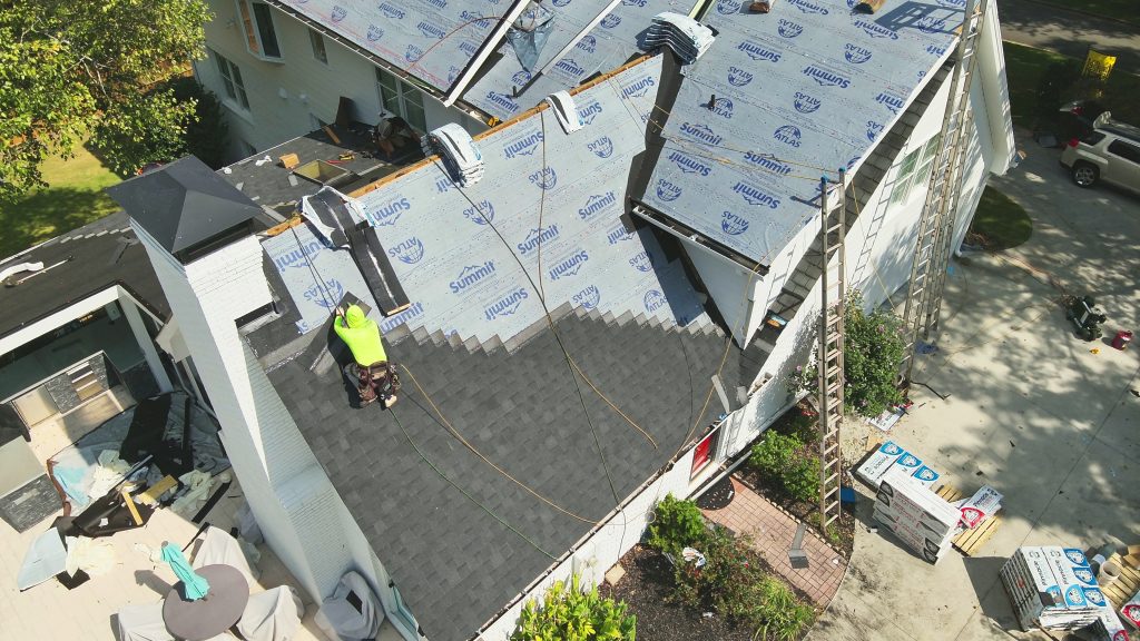 Drone image of a roofer replacing a roof with the best asphalt shingles.