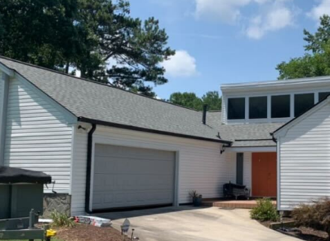 Photo looking at new black Gutters and downspouts on a home