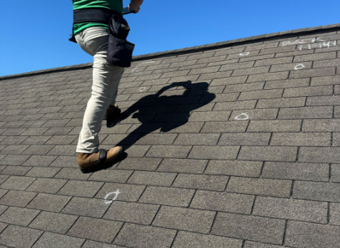 Image of a roofer inspecting a residential shingle roof during a roof inspection