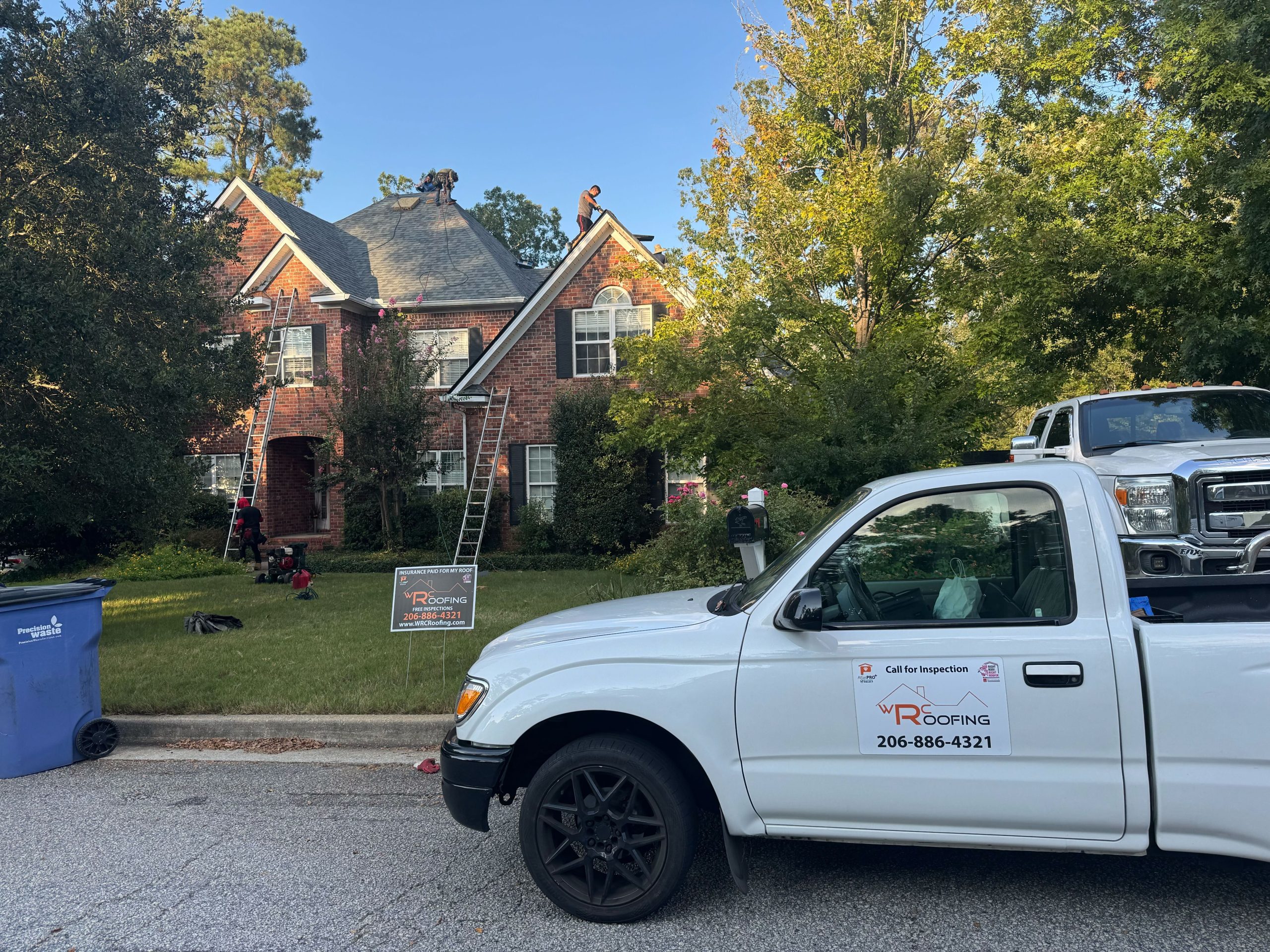 Image of a Whitaker Roofing Company vehicle in front of a house having the roof replaced